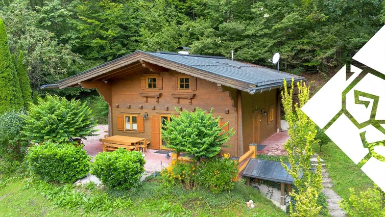 Charmantes Holzhaus im Chalet-Stil mit gepflasterter Terrasse und umgebender Natur.