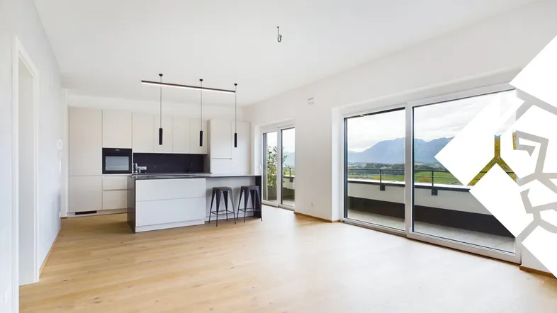 Helles, offenes Wohnzimmer mit integrierter Küche, Holzboden und Zugang zur Terrasse mit Bergblick.