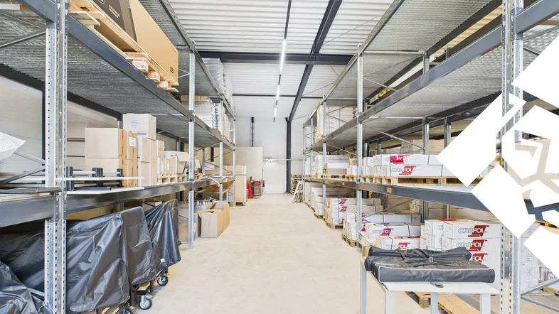 Geräumige Lagerhalle mit hohen Decken, Metallregalen und Betonboden, ideal für Logistik und Lagerung.