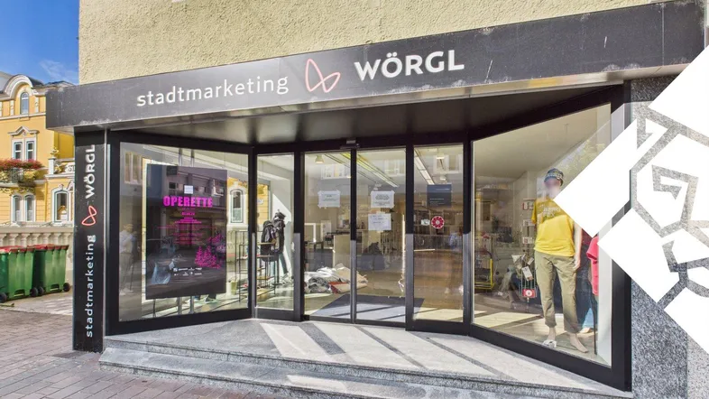 Eingangsbereich eines Geschäftsgebäudes mit großen Glasfronten und Beschilderung in Wörgl.