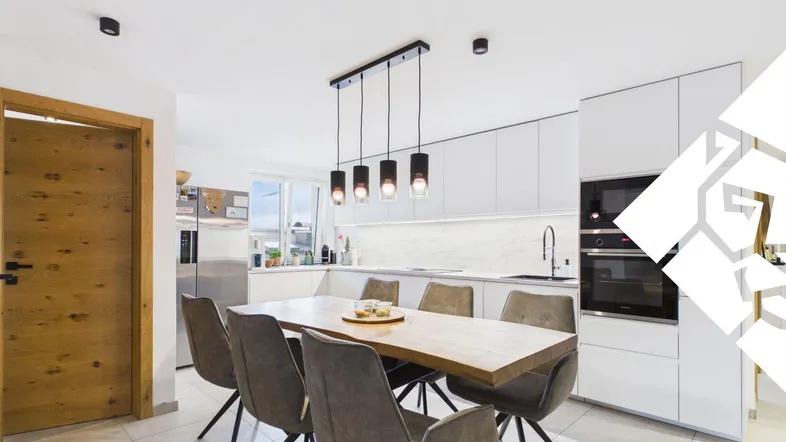 Moderne offene Küche mit Essbereich, weißen Schränken und Holztisch, ideal für gesellige Mahlzeiten.