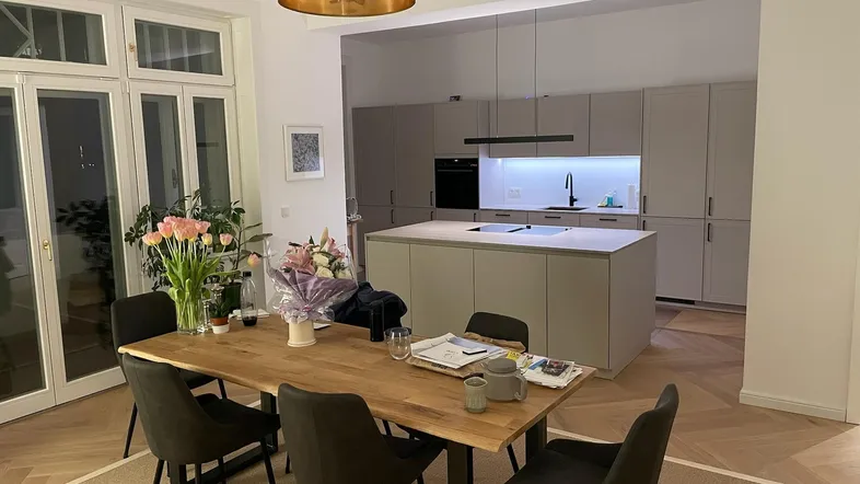 Geräumiger offener Wohn- und Essbereich mit moderner Küche und Zugang zum Balkon.