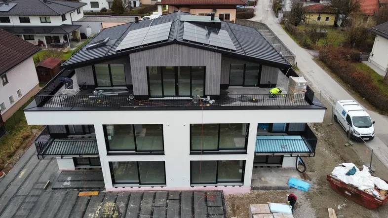 Neubau-Mehrfamilienhaus mit moderner Architektur, Flachdach und Photovoltaikanlage auf dem Dach.