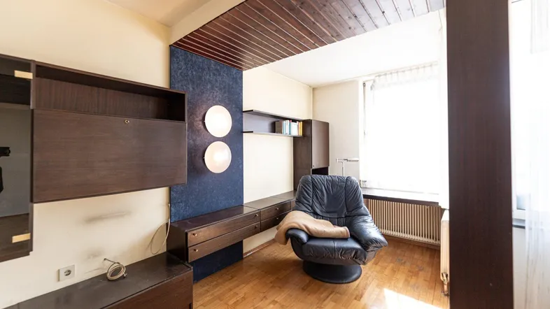 Gemütliches Wohnzimmer mit Holzdecke, Parkettboden und einer bequemen Ledersessel-Ecke.