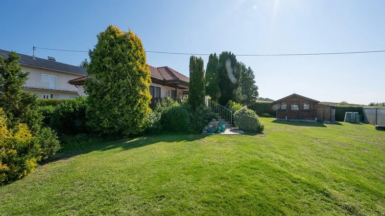 Großer, gepflegter Garten mit Rasenfläche und Blick auf das Einfamilienhaus unter strahlendem Sonnenschein.
