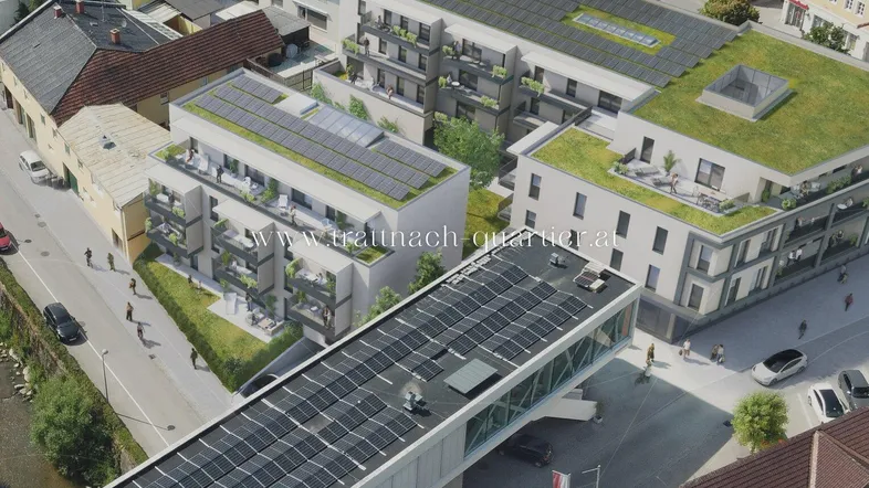 Luftaufnahme eines modernen Wohnkomplexes mit Solaranlagen und begrünten Dächern in städtischer Umgebung.