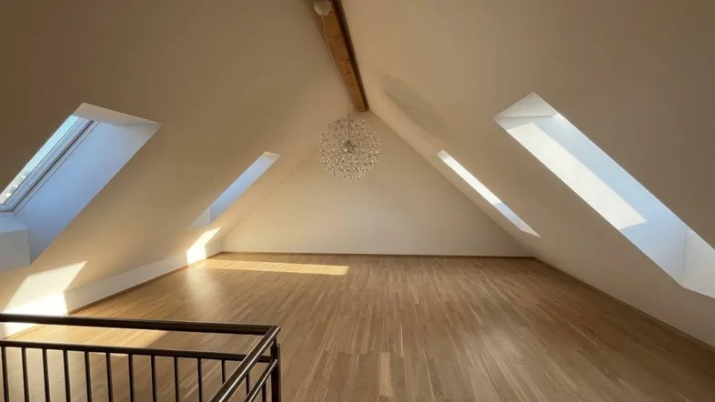 Geräumiger Dachboden mit Holzbalken, Dachfenstern und hellem Parkettboden, ideal für Ausbau.