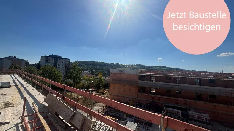 Blick über eine Baustelle bei sonnigem Wetter, mit neuen Gebäudestrukturen und einer weiten Aussicht.