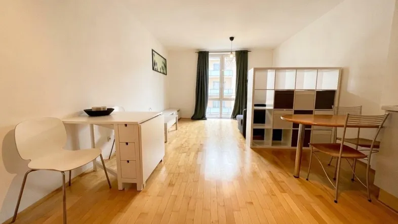 Helles Wohnzimmer mit Parkettboden, Esstisch und Blick nach draußen durch große Fenster.