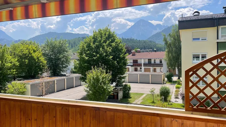 Geräumiger Balkon mit Holzboden und Markise, bietet einen weiten Blick auf die umliegende Berglandschaft.