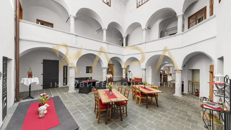 Historischer Innenhof mit Arkaden, Sitzgelegenheiten und Steinfliesenboden, ideal für Veranstaltungen.