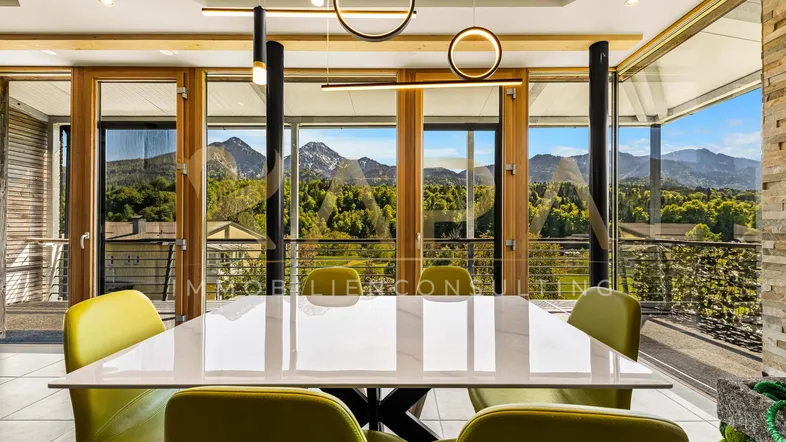 Moderner Essbereich mit großem Tisch, Designerleuchten und beeindruckendem Bergblick durch bodentiefe Fenster.