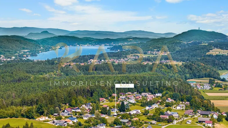 Luftaufnahme eines Dorfes mit See und Bergen im Hintergrund, die Immobilie ist markiert.