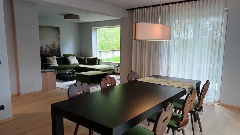 Geräumiger Wohn-Essbereich mit modernem Esstisch, bequemer Couch und Blick ins Grüne.