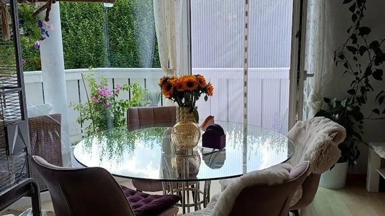 Helles Esszimmer mit rundem Glastisch, modernen Stühlen und direktem Zugang zum Balkon.