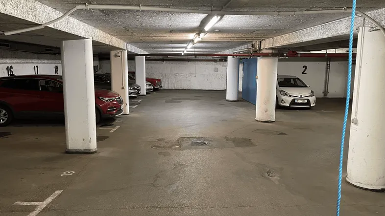 Geräumige Tiefgarage mit mehreren Stellplätzen, Betonpfeilern und einfacher Beleuchtung.