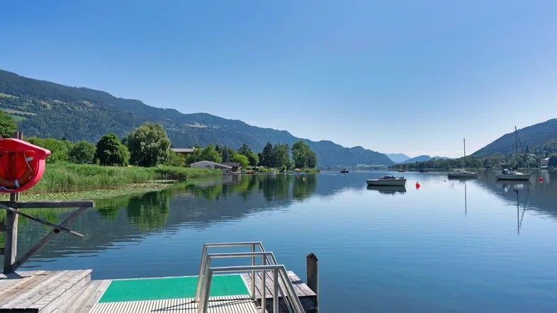 Malerischer Blick auf den See mit umliegenden Bergen und einem Steg zum Schwimmen.