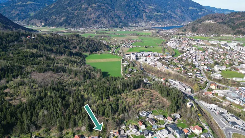 Luftaufnahme einer Wohnsiedlung am Waldrand mit weitem Blick auf Berge und Tal.