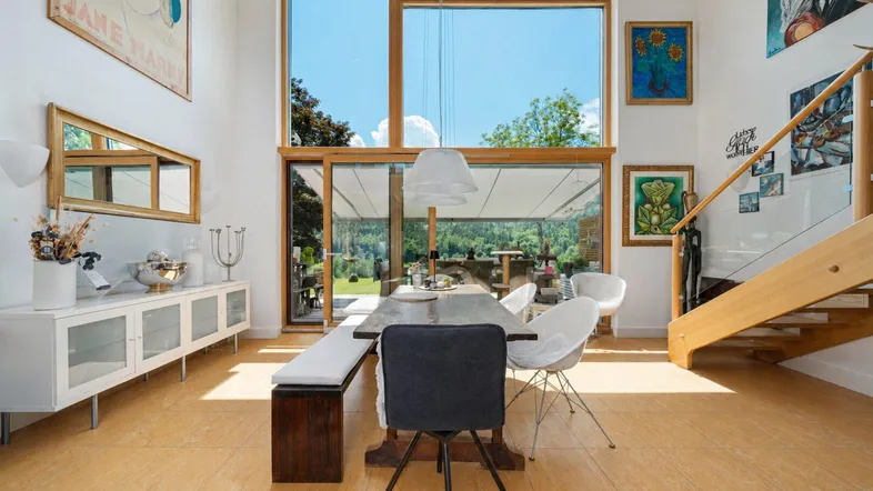 Helles Esszimmer mit hohen Decken, großen Fenstern und Zugang zum Gartenbereich.