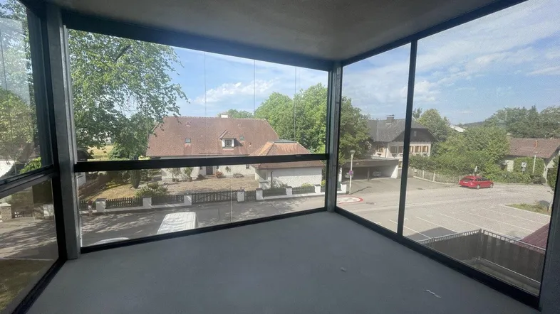 Verglaste Loggia mit Blick auf die umliegende Wohngegend und viel Tageslicht.