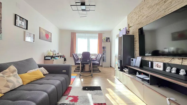 Helles Wohn- und Esszimmer mit modernem Sofa, Esstisch und dekorativer Steinwand.