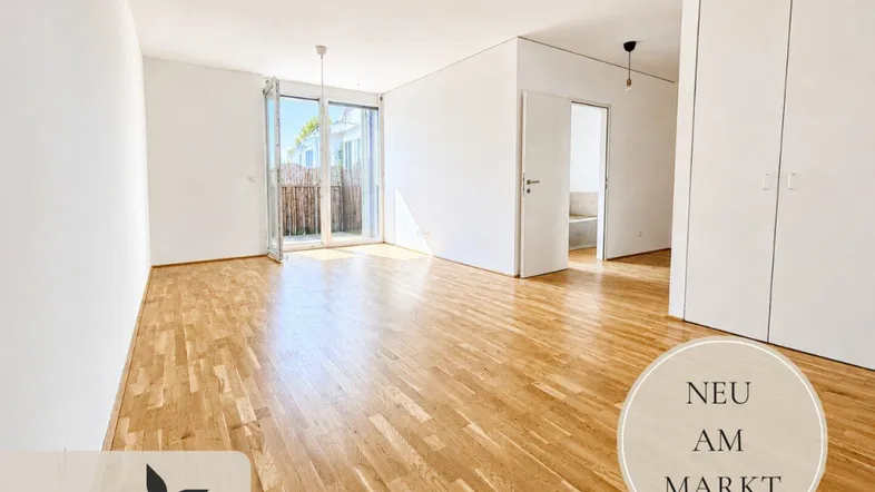 Heller, leerer Raum mit modernem Parkettboden, Zugang zum Balkon und integrierten Einbauschränken.