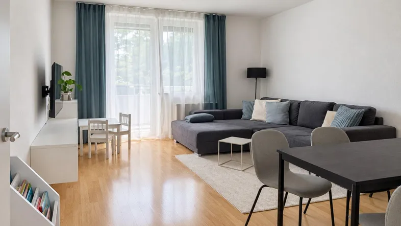 Heller Wohn- und Essbereich mit modernem Sofa, Esstisch und Zugang zum Balkon.