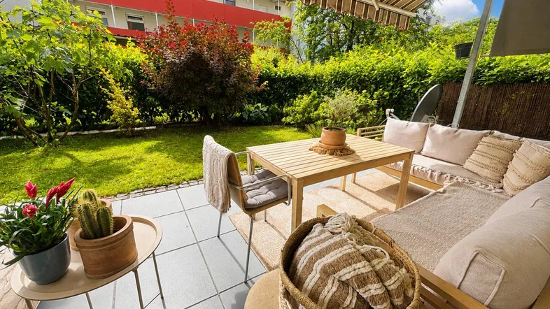 Gemütliche Terrasse mit bequemen Gartenmöbeln, Markise und üppigem Grünblick.