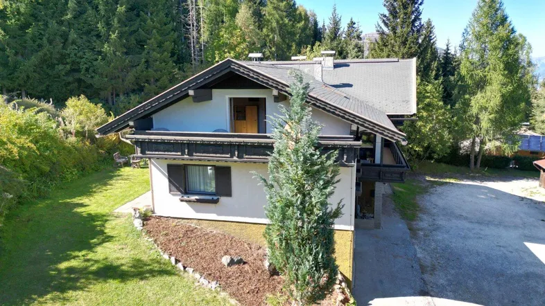 Traditionelles Haus in den Bergen mit Holzbalkonen und umgeben von üppiger Natur.