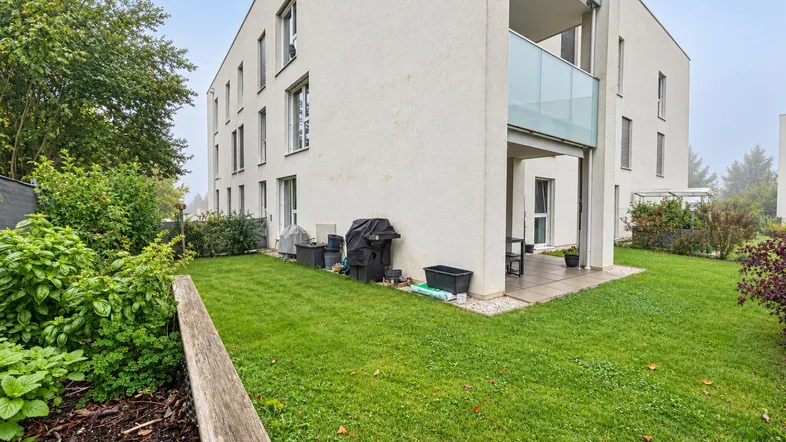 Moderner Apartmentkomplex mit gepflegtem Gartenbereich und kleiner Terrasse im Erdgeschoss.