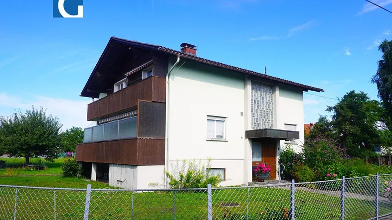 Ansicht des Hauses mit zwei Balkonen, umgeben von einem Garten und viel Grün.