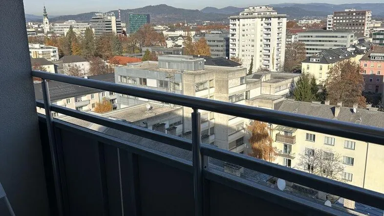 Balkon mit Metallgeländer und Stuhl, bietet einen weiten Blick über die Stadt.