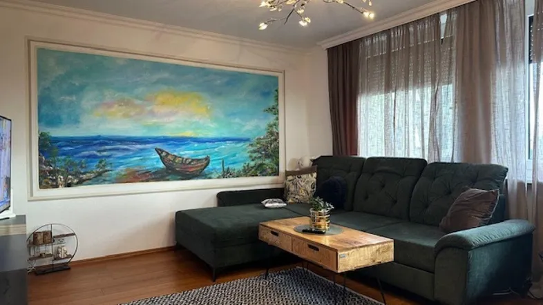 Gemütliches Wohnzimmer mit großem Wandgemälde, bequemer Couch und Holzboden.