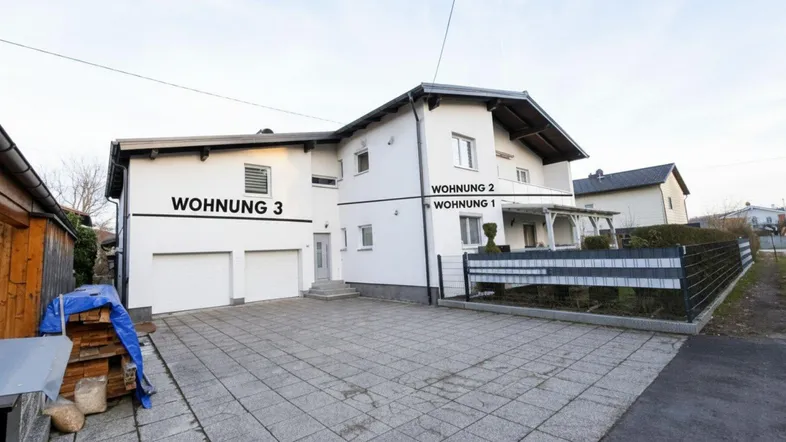 Vorderansicht des Hauses mit drei Wohneinheiten und gepflastertem Vorplatz.