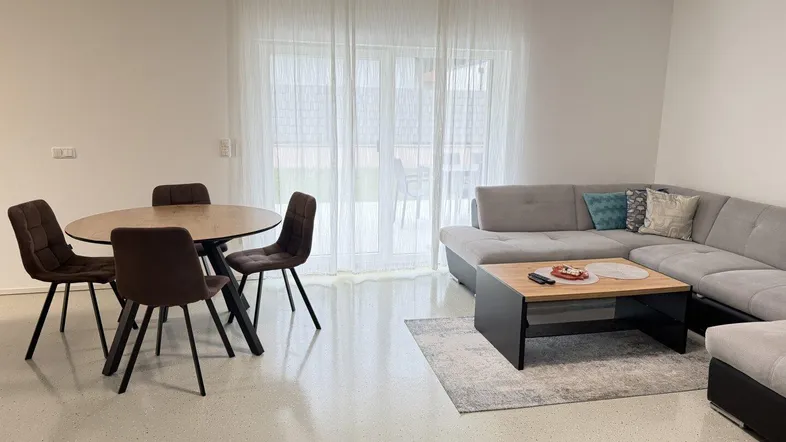 Heller Wohn-Essbereich mit modernem Sofa, Esstisch und Zugang zur Terrasse.
