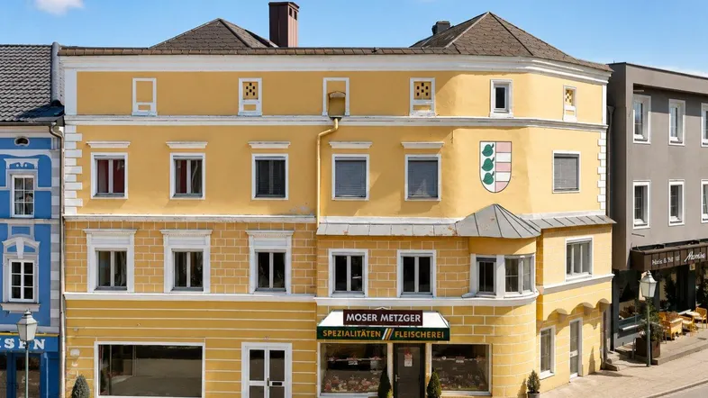 Historisches Gebäude mit gelber Fassade und traditioneller Architektur in einer städtischen Umgebung.
