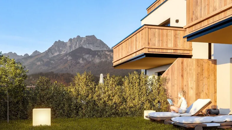Moderne Wohnanlage mit Holzfassade und gepflegtem Gartenbereich, umgeben von einer beeindruckenden Bergkulisse.