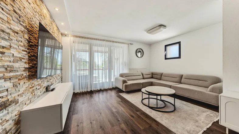 Helles Wohnzimmer mit großem Sofa, Medieneinheit und dekorativer Steinwand.