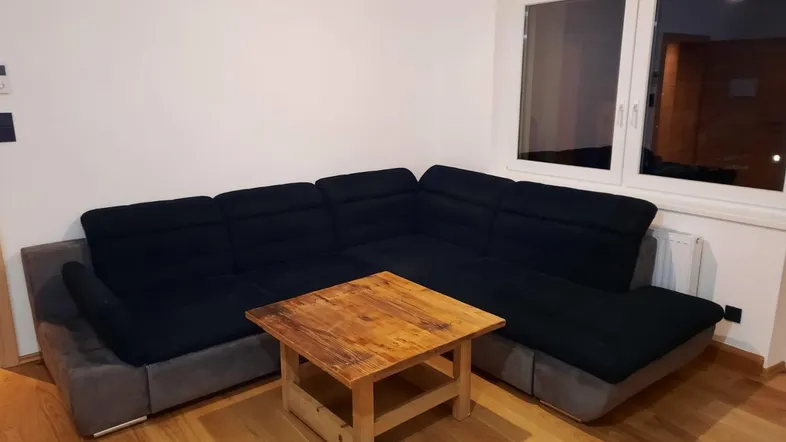 Gemütliches Wohnzimmer mit Ecksofa, Holztisch und hellem Parkettboden.