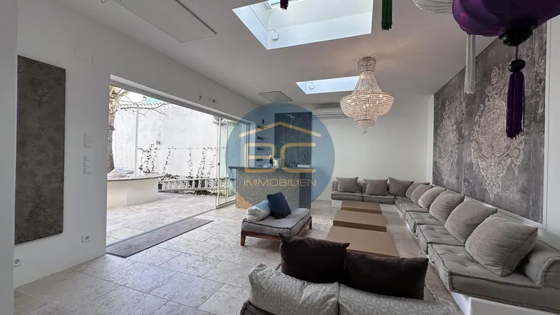Geräumiges Wohnzimmer mit großen Sofas, Oberlichtern und Zugang zum Außenbereich.