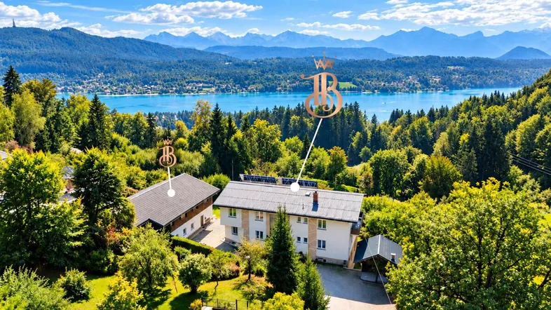 Luftaufnahme des Anwesens mit mehreren Gebäuden, umgeben von üppiger Natur und einem See im Hintergrund.