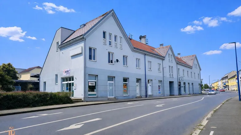 Gebäudeansicht von der Straße mit mehreren Einheiten und Geschäften im Erdgeschoss.