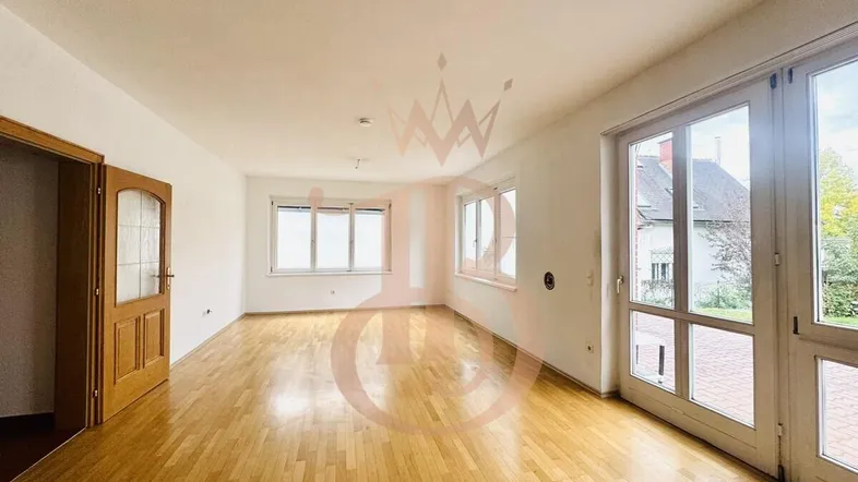 Helles Wohnzimmer mit Parkettboden und großen Fenstern, die Zugang zum Garten bieten.