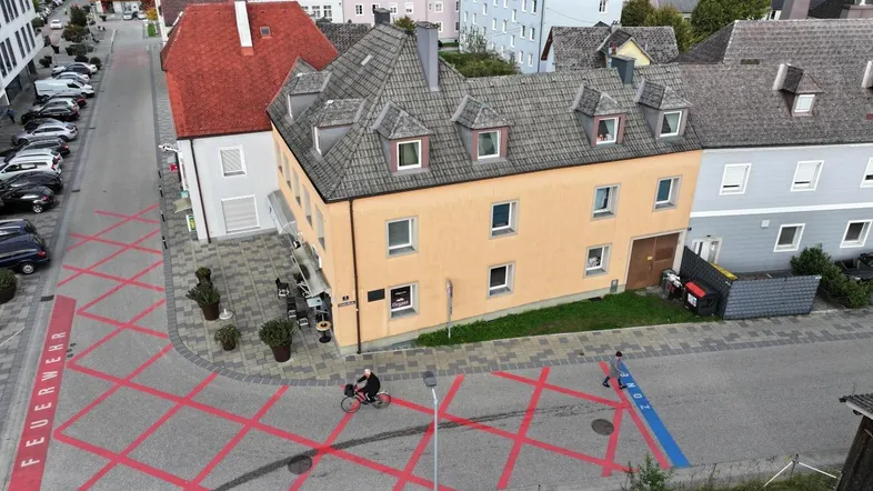 Luftaufnahme eines Gebäudes mit orangefarbener Fassade an einer Straße in einer städtischen Umgebung.