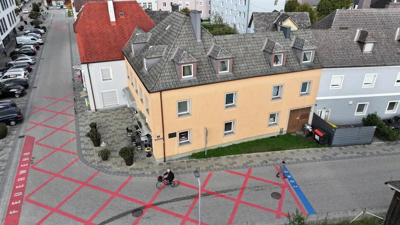 Luftaufnahme eines Gebäudes in einer städtischen Umgebung mit umliegenden Häusern und Straßen.