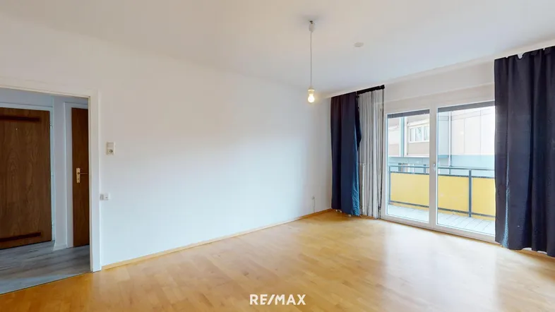 Helles Wohnzimmer mit Parkettboden und Zugang zu einem Balkon, ideal für entspannte Stunden.