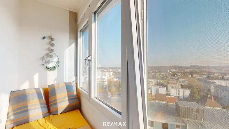 Helle Loggia mit gemütlicher Sitzbank und weitem Blick über die Stadt.