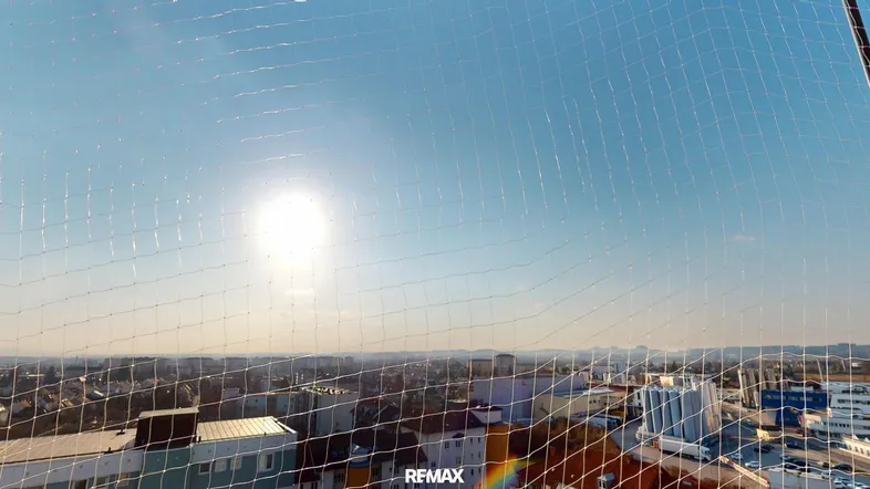 Sonniger Ausblick über die Stadtlandschaft an einem klaren Tag, durch ein Schutznetz.