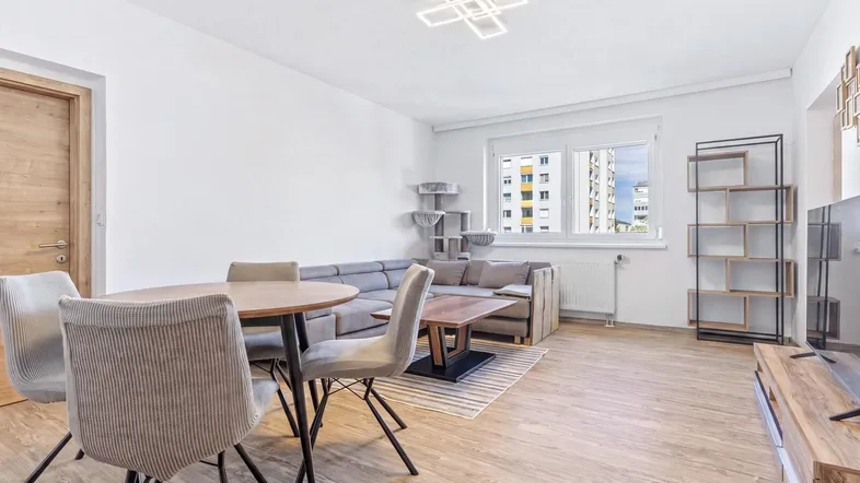 Helles Wohn- und Esszimmer mit modernem Design, Holzboden und Blick auf die Stadt.