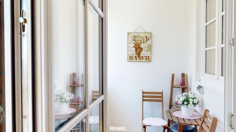 Gemütlicher, verglaster Balkon mit kleiner Sitzecke und rustikaler Dekoration.